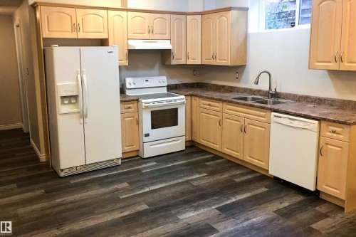Kitchen featuring light wood finish cabinets, white appliances, and dark wood-style floors - 10623 75 Avenue, Edmonton, AB - Indoor Photo Showing Kitchen With Double Sink