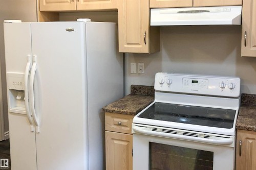 Kitchen featuring white appliances, dark countertops, and light wood finish cabinets - 10623 75 Avenue, Edmonton, AB - Indoor Photo Showing Kitchen