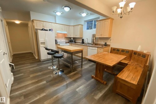 Kitchen featuring white appliances, suspended lighting, dark wood finished floors, and light countertops - 10623 75 Avenue, Edmonton, AB - Indoor Photo Showing Kitchen With Double Sink