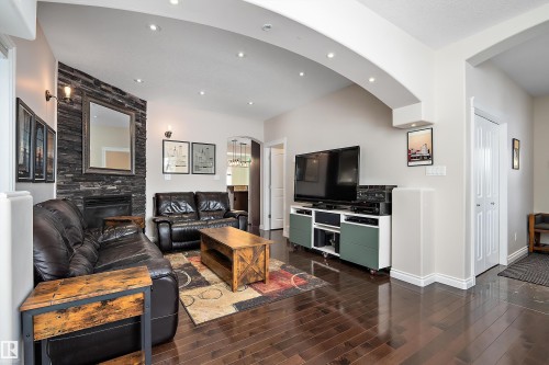 Living area with arched walkways, a fireplace, dark wood-style floors, and recessed lighting - 10623 75 Avenue, Edmonton, AB - Indoor