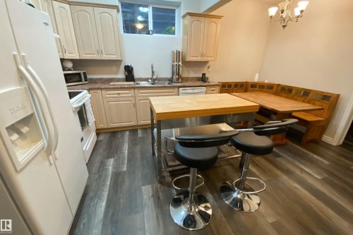 Kitchen featuring white appliances, dark wood finished floors, and suspended lighting - 10623 75 Avenue, Edmonton, AB - Indoor