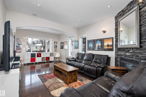 Living room featuring arched walkways, a fireplace, dark wood-style flooring, and recessed lighting - 10623 75 Avenue, Edmonton, AB - Indoor Photo Showing Living Room
