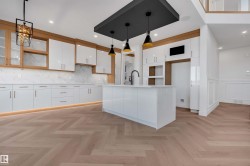 Kitchen featuring white cabinets, parquet floors, an island with sink, backsplash, and glass fronted cabinets - 