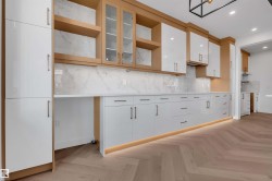 Kitchen featuring parquet floors, white cabinets, glass insert cabinets, recessed lighting, and light stone countertops - 