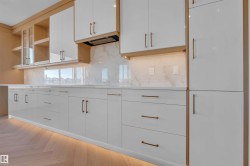 Kitchen featuring white cabinets, parquet floors, open shelves, light stone counters, and backsplash - 