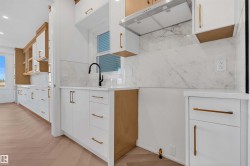 Dual tone kitchen featuring light wood-type flooring, light stone counters, dual tone cabinets, backsplash, and modern cabinets - 