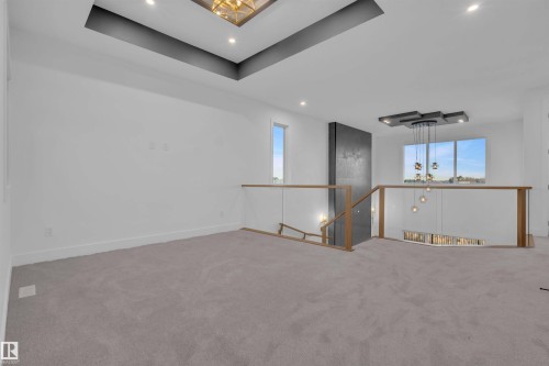 Carpeted empty room featuring a chandelier, a raised ceiling, and plenty of natural light - 108 Eldridge Point(E), St. Albert, AB - Indoor Photo Showing Other Room