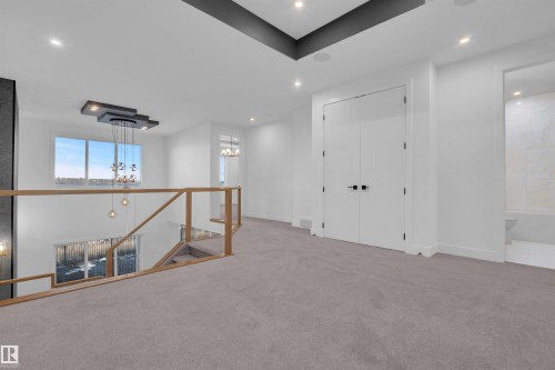 Carpeted spare room featuring suspended lighting and baseboards - 108 Eldridge Point(E), St. Albert, AB - Indoor Photo Showing Other Room