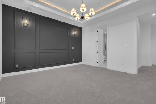 Unfurnished bedroom featuring a chandelier, a tray ceiling, light carpet, and a decorative wall - 108 Eldridge Point(E), St. Albert, AB - Indoor Photo Showing Other Room
