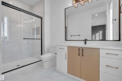 Bathroom featuring vanity, a marble finish shower, healthy amount of natural light, and light marble finish flooring - 