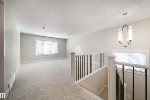 Hallway with an upstairs landing, light carpet, and a textured ceiling - 2237 56 Street, Edmonton, AB - Indoor Photo Showing Other Room