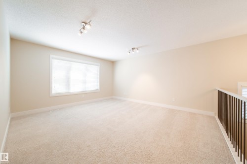 Spare room with rail lighting, light colored carpet, and a textured ceiling - 2237 56 Street, Edmonton, AB - Indoor Photo Showing Other Room