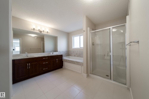 Bathroom with double vanity, a shower stall, a textured ceiling, light tile patterned floors, and a garden tub - 2237 56 Street, Edmonton, AB - Indoor Photo Showing Bathroom