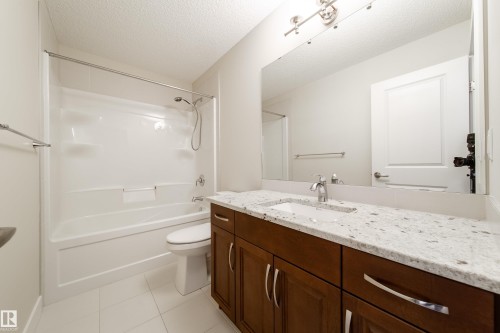 Bathroom featuring vanity, a textured ceiling, tub / shower combination, and light tile patterned floors - 2237 56 Street, Edmonton, AB - Indoor Photo Showing Bathroom