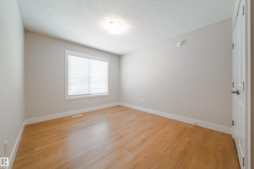 Unfurnished room with a textured ceiling and light wood-style floors - 2237 56 Street, Edmonton, AB - Indoor Photo Showing Other Room