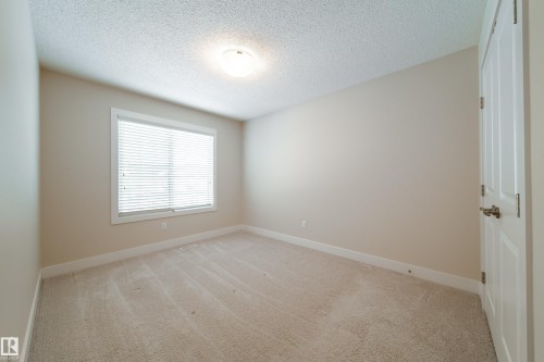 Empty room with a textured ceiling and light carpet - 2237 56 Street, Edmonton, AB - Indoor Photo Showing Other Room
