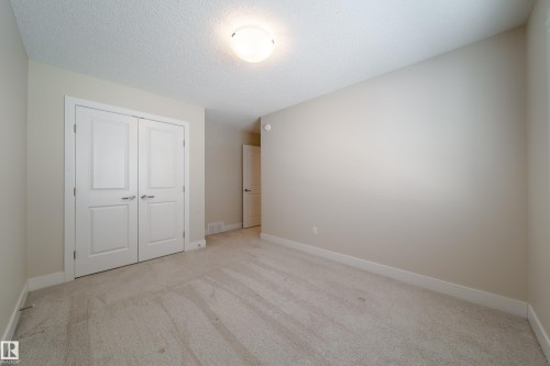 Unfurnished bedroom featuring light colored carpet, a textured ceiling, and a closet - 2237 56 Street, Edmonton, AB - Indoor Photo Showing Other Room