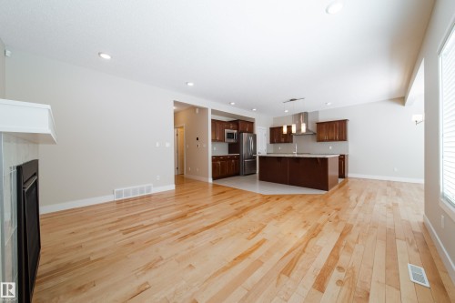 Unfurnished living room with light wood-type flooring, a fireplace, and recessed lighting - 2237 56 Street, Edmonton, AB - Indoor Photo Showing Kitchen
