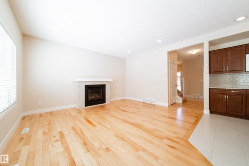 Unfurnished living room featuring light wood-type flooring, a tiled fireplace, and recessed lighting - 2237 56 Street, Edmonton, AB - Indoor Photo Showing Living Room With Fireplace