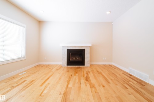 Unfurnished living room featuring light wood finished floors, a tile fireplace, and recessed lighting - 2237 56 Street, Edmonton, AB - Indoor Photo Showing Living Room With Fireplace