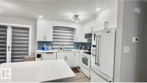 Kitchen featuring white appliances, recessed lighting, white cabinets, tasteful backsplash, and light wood-type flooring - 2915 145 Avenue, Edmonton, AB - Indoor Photo Showing Kitchen With Double Sink With Upgraded Kitchen