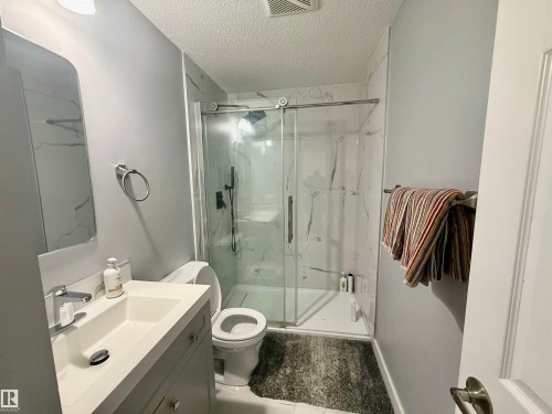 Full bathroom featuring vanity, a textured ceiling, and a marble finish shower - 2915 145 Avenue, Edmonton, AB - Indoor Photo Showing Bathroom