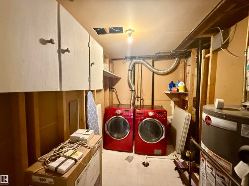 Laundry room featuring light flooring, water heater, washing machine and clothes dryer, and cabinet space - 2915 145 Avenue, Edmonton, AB - Indoor