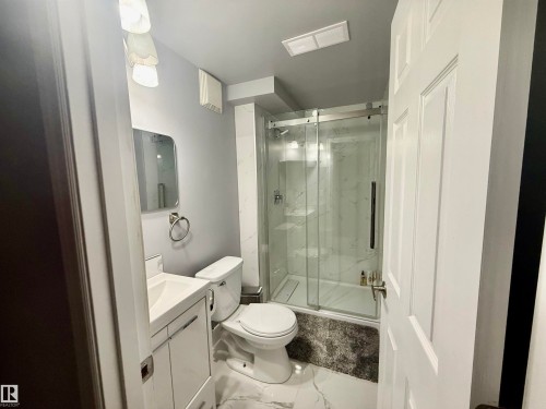 Full bathroom with vanity, marble look tiles, and a marble finish shower - 2915 145 Avenue, Edmonton, AB - Indoor Photo Showing Bathroom