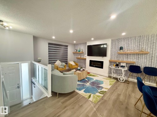 Living area featuring a textured ceiling, an accent wall, a glass covered fireplace, light wood-style floors, and recessed lighting - 2915 145 Avenue, Edmonton, AB - Indoor With Fireplace