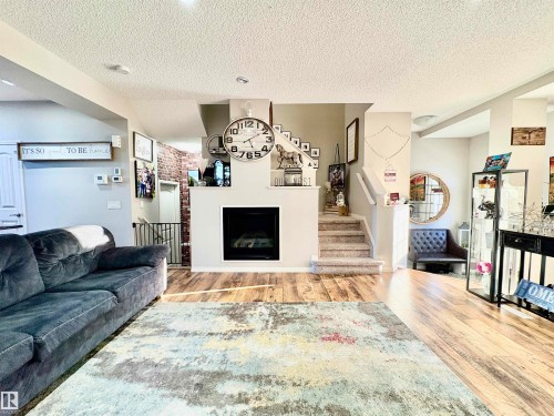Living area with light wood finished floors, a fireplace, and a textured ceiling - 425 Sheppard Boulevard, Leduc, AB - Indoor Photo Showing Living Room With Fireplace