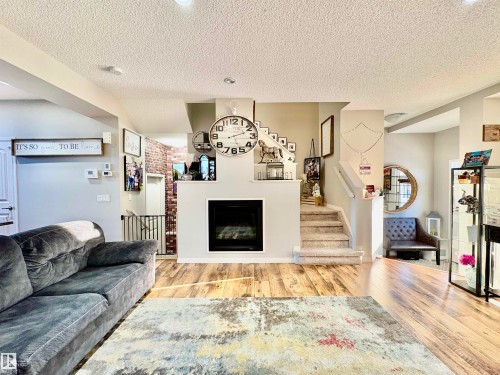 Living area featuring a fireplace, light wood finished floors, and a textured ceiling - 425 Sheppard Boulevard, Leduc, AB - Indoor Photo Showing Living Room With Fireplace