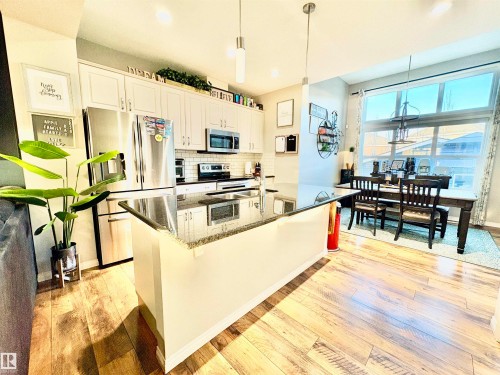 Kitchen with light wood-type flooring, stainless steel appliances, hanging light fixtures, and white cabinets - 425 Sheppard Boulevard, Leduc, AB - Indoor Photo Showing Kitchen With Stainless Steel Kitchen With Upgraded Kitchen