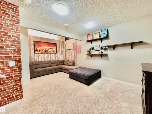 Carpeted living room featuring a textured ceiling and baseboards - 425 Sheppard Boulevard, Leduc, AB - Indoor Photo Showing Other Room