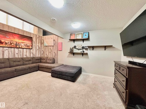 Living area with a textured ceiling, wooden walls, and light colored carpet - 425 Sheppard Boulevard, Leduc, AB - Indoor