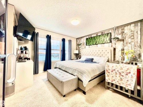 Bedroom featuring a textured ceiling, light carpet, wood walls, and an accent wall - 425 Sheppard Boulevard, Leduc, AB - Indoor Photo Showing Bedroom