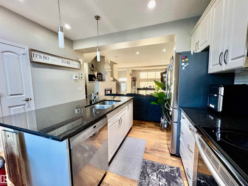 Kitchen with white cabinetry, a center island with sink, stainless steel appliances, dark stone counters, and open floor plan - 425 Sheppard Boulevard, Leduc, AB - Indoor Photo Showing Kitchen With Stainless Steel Kitchen With Double Sink With Upgraded Kitchen