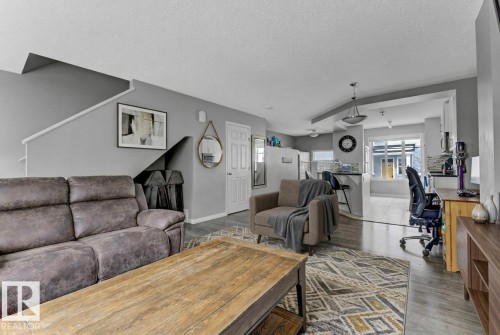 Living room featuring an office area, plenty of natural light, a textured ceiling, and light wood-style flooring - #127 2905 141 Street, Edmonton, AB - Indoor Photo Showing Living Room