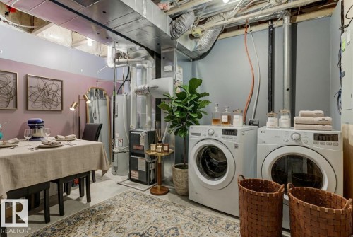 Laundry area with finished concrete flooring, gas water heater, washing machine and clothes dryer, and heating unit - #127 2905 141 Street, Edmonton, AB - Indoor Photo Showing Laundry Room