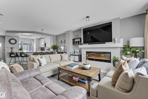 Living room with a glass covered fireplace and a textured ceiling - #127 2905 141 Street, Edmonton, AB - Indoor Photo Showing Living Room With Fireplace