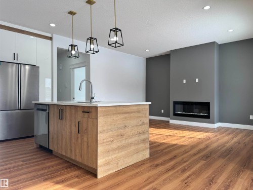 Kitchen featuring stainless steel appliances, a kitchen island with sink, modern cabinets, hanging light fixtures, and two tone color scheme - 1703 152 Avenue, Edmonton, AB - Indoor Photo Showing Kitchen With Upgraded Kitchen