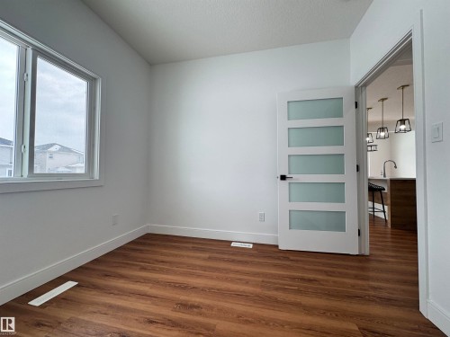 Unfurnished bedroom featuring dark wood-style floors and a textured ceiling - 1703 152 Avenue, Edmonton, AB - Indoor Photo Showing Other Room