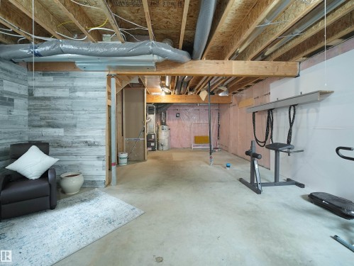 Unfinished basement with wood walls and gas water heater - 8921 217 St Nw, Edmonton, AB - Indoor Photo Showing Basement