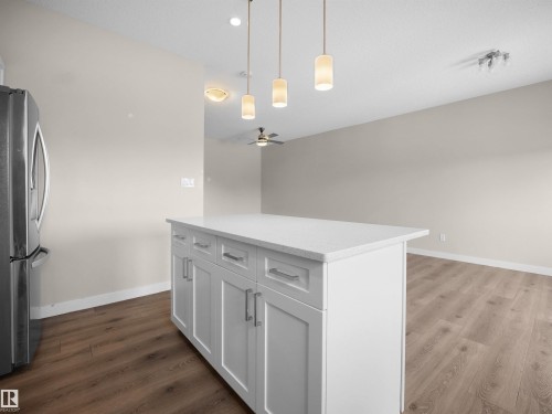Kitchen featuring a kitchen island, stainless steel fridge, dark wood-style flooring, and pendant lighting - 8921 217 St Nw, Edmonton, AB - Indoor