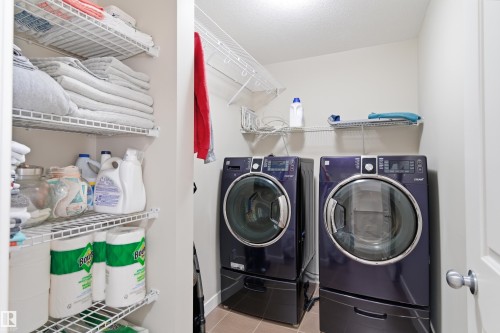 Laundry area featuring washer and dryer and light tile patterned floors - 149 Hawks Ridge Boulevard, Edmonton, AB - Indoor Photo Showing Laundry Room