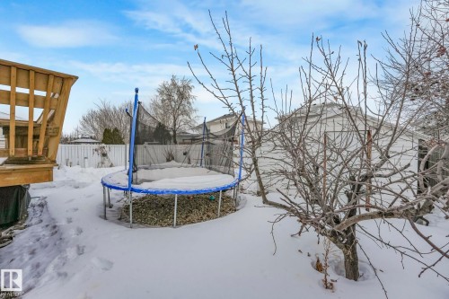 Yard layered in snow featuring a trampoline and a fenced backyard - 4720 150 Avenue, Edmonton, AB - Outdoor