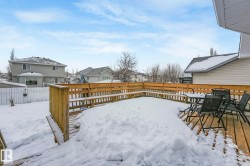 Yard covered in snow with a deck, a fenced backyard, a residential view, and outdoor dining space - 