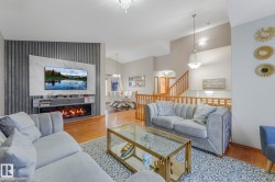 Living area with an accent wall, wood finished floors, lofted ceiling, a glass covered fireplace, and wallpapered walls - 