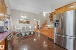 Kitchen with appliances with stainless steel finishes, granite floors, pendant lighting, glass insert cabinets, and a chandelier - 