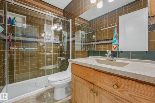 Bathroom with vanity, tile walls, a shower stall, and light tile patterned floors - 4720 150 Avenue, Edmonton, AB - Indoor Photo Showing Bathroom