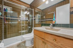 Bathroom with vanity, tile walls, a shower stall, and light tile patterned floors - 